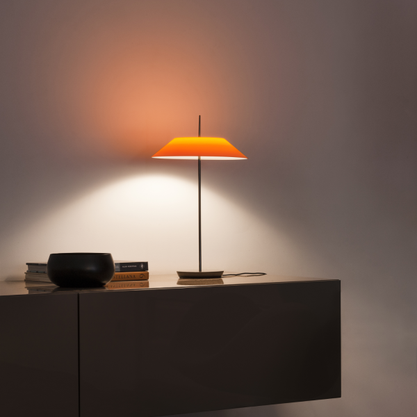 Tischleuchte Mayfair 5500 von Vibia mit orangem Schirm auf einem dunklen Sideboard