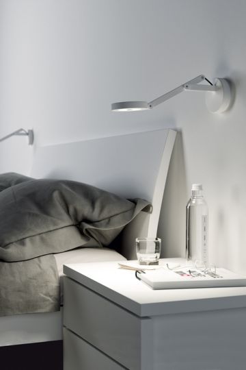 Weiße schwenkbare Wandleuchte String von Rotaliana über einem Nachttisch neben dem Bett